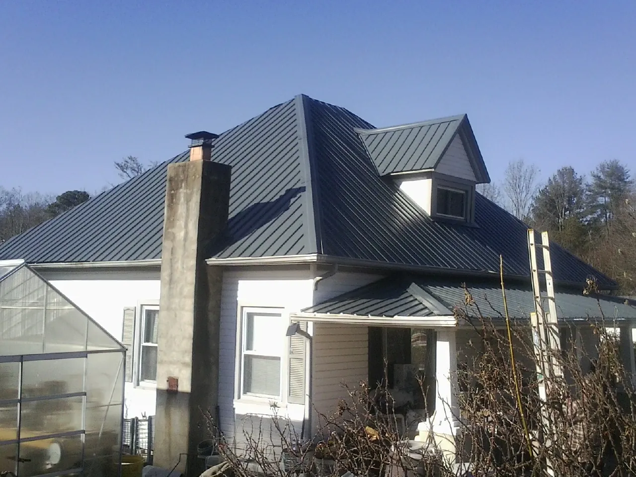 Dark blue standing seam metal roof on a white farmhouse with dormer — Slate & Tile Roof Repair by Roofing Brothers in Marblehead