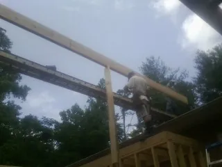 Carpenter setting a ridge beam over a new addition frame — Ice Dam Removal by Roofing Brothers in Marblehead