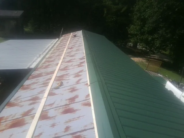 Old rusted panels beside newly installed green metal roofing — Wind Damage Roof Repair by Roofing Brothers in Marblehead