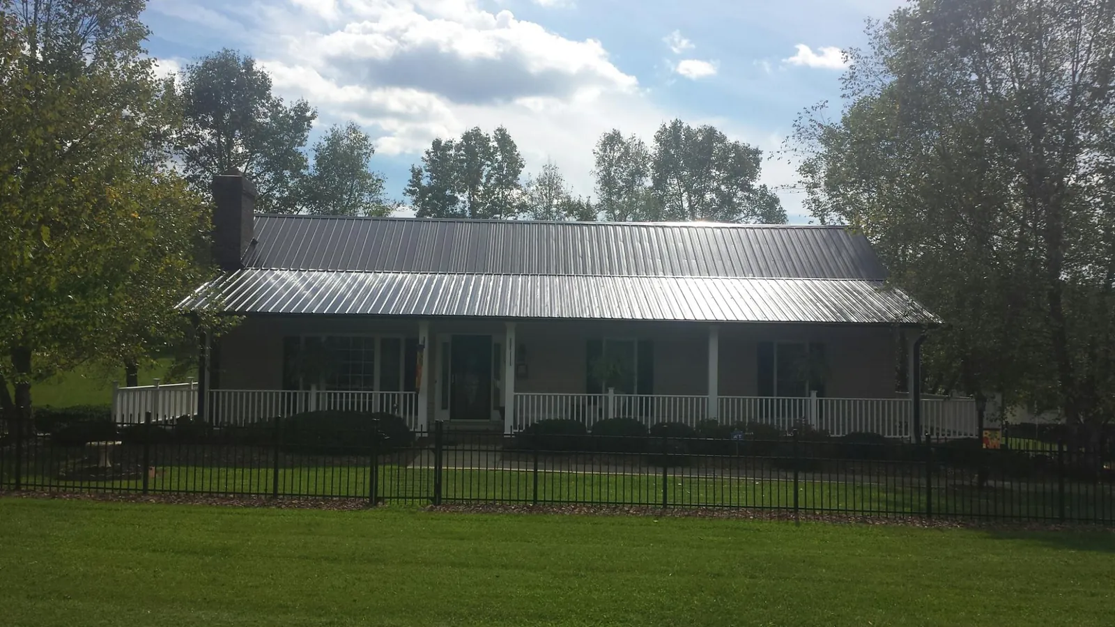 Gray metal roof on a brick ranch with a full width front porch — Gutter Guard Installation work by our crew in Marblehead