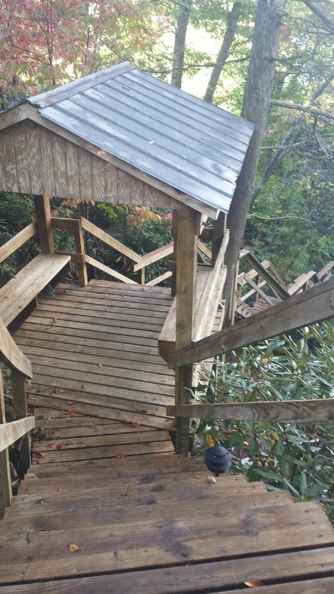 Metal roofed shelter over wooden steps on a wooded walkway — Skylight Repair & Installation work by our crew in Marblehead