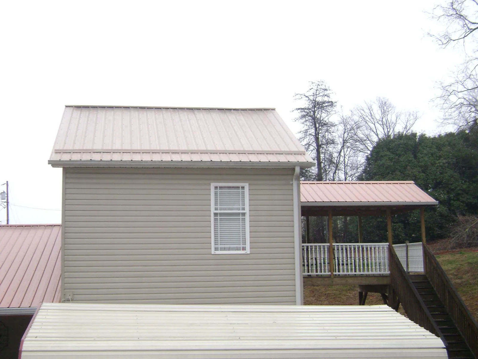 Tan metal roofs on a two story addition and attached porch, from a Roof Replacement job in Marblehead